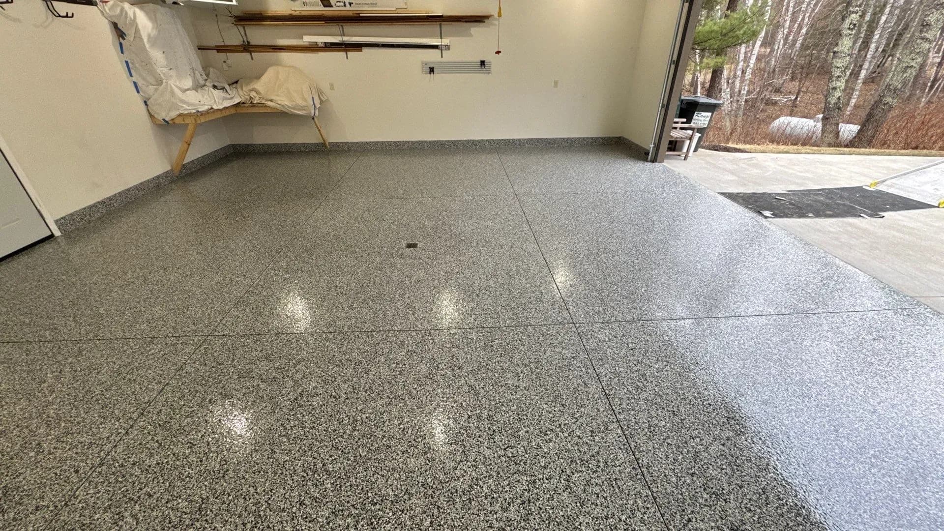 A garage with a newly-coated black, gray, and white flecked concrete floor.