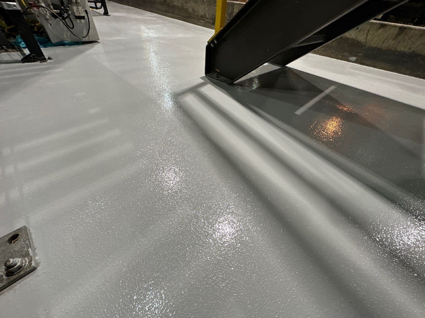 A close-up of a commercial warehouse space with textured, light gray Urethane cement concrete coated flooring.