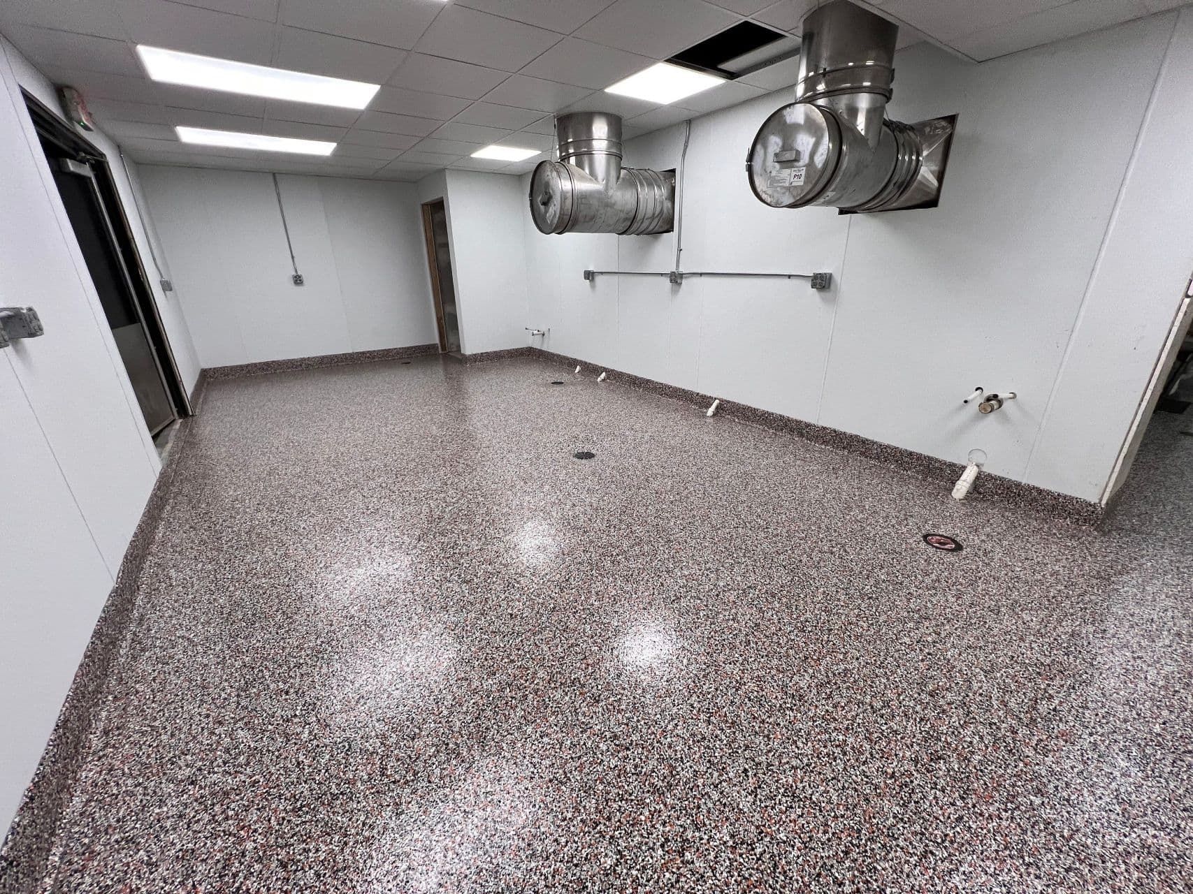 A commercial restaurant kitchen space with newly-coated black, white, and red flake concrete flooring.