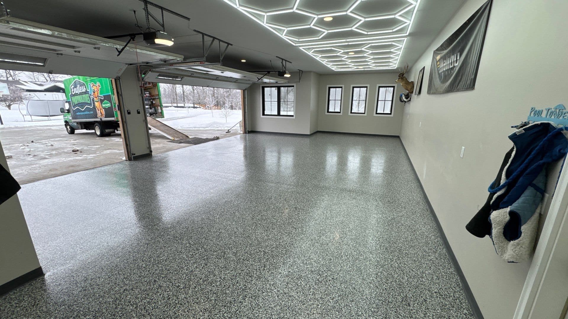 A garage with geometric hexagonal overhead lighting and a newly-coated black, white, and gray concrete floor.