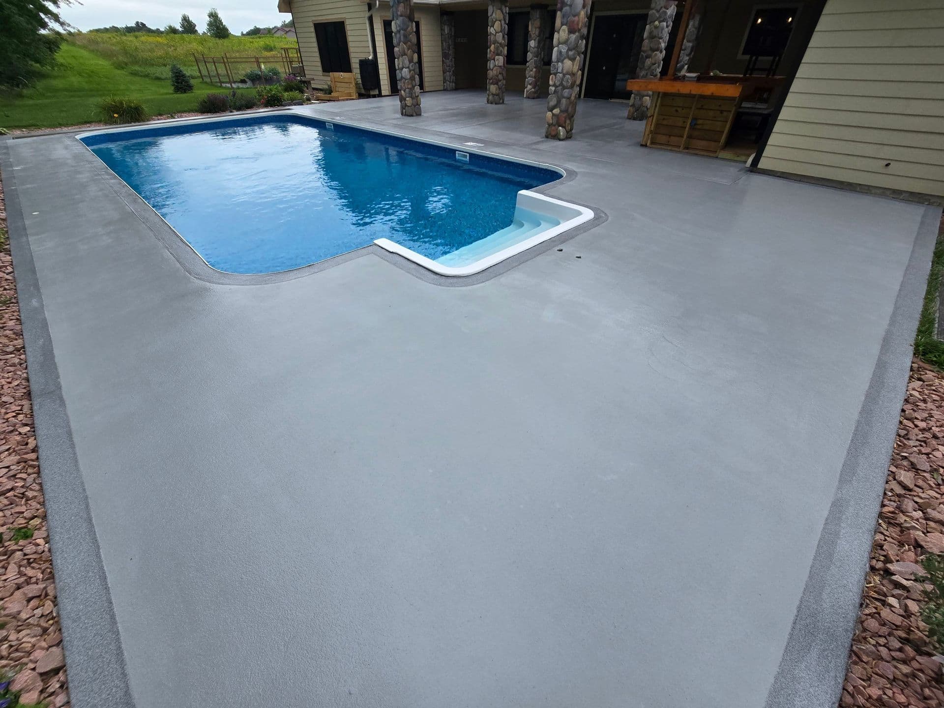 A pool with newly-coated solid gray color concrete deck.
